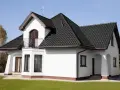 Biały dom z ciemnym dachem. Czy to kolor ral 7016? Elegancka biel ścian kontrastuje z grafitową dachówką.