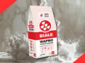 Białe wapno budowlane w worku, otoczone chmurą białego pyłu. Idealne do prac remontowych.