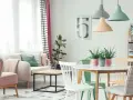 Jasne, oto opis:

Salon w stylu skandynawskim, gdzie dominują **kolory pastelowe**. Miękka sofa, różowe fotele i zielone akcenty tworzą przytulną atmosferę.