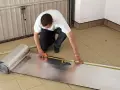 Mężczyzna mierzy materiał do ocieplenia bramy garażowej.