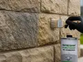 Pędzel z impregnatem hydrofobowym do kamienia nakładany na kamienną ścianę z kroplami wody.