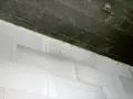 Piana montażowa wypełnia szczelinę między betonowym stropem a białą ścianą z bloczków, tworząc dylatację.