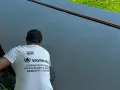 Pracownik w koszulce z napisem "POSADZKI ŻYWICZNE" kończy pracę nad nową, lśniącą posadzką.