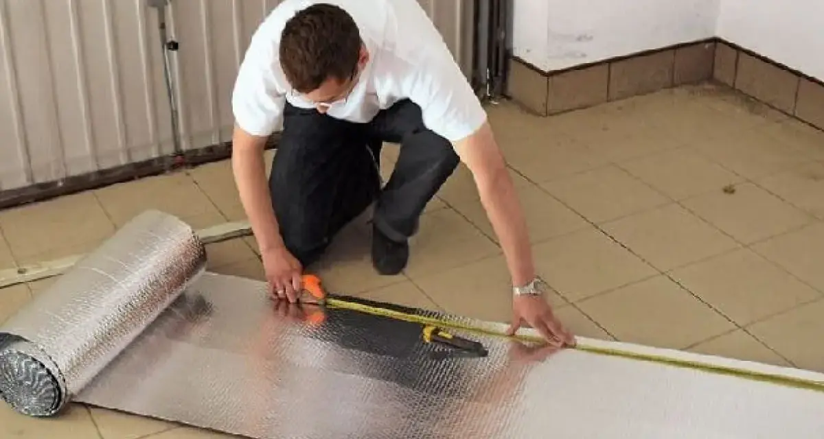Mężczyzna mierzy materiał do ocieplenia bramy garażowej.