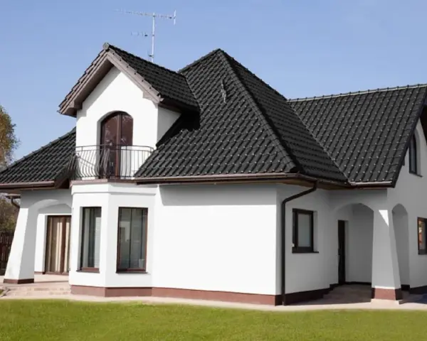 Biały dom z ciemnym dachem. Czy to kolor ral 7016? Elegancka biel ścian kontrastuje z grafitową dachówką.