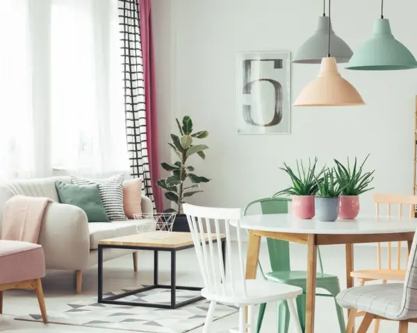 Jasne, oto opis:

Salon w stylu skandynawskim, gdzie dominują **kolory pastelowe**. Miękka sofa, różowe fotele i zielone akcenty tworzą przytulną atmosferę.