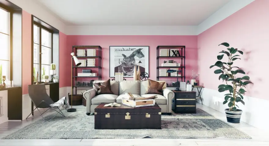 Salon z róż indyjski na ścianach. Wygodna sofa, stylowa skrzynia i regały pełne książek tworzą przytulną atmosferę.