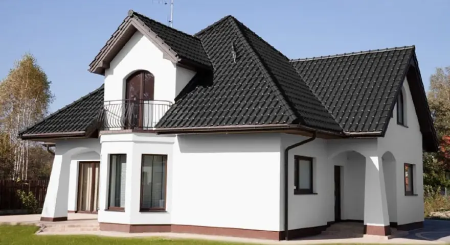 Biały dom z ciemnym dachem. Czy to kolor ral 7016? Elegancka biel ścian kontrastuje z grafitową dachówką.