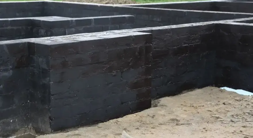 Fundament betonowy z czarnym abizolem, gotowy na kolejne etapy budowy.