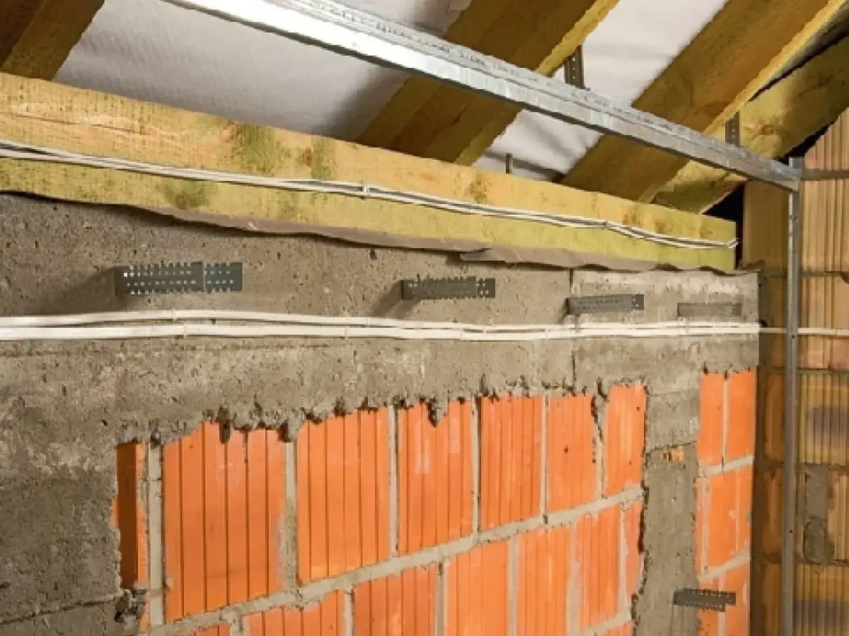 Budowa ścianki działowej: widoczny profil v, cegły, beton, wełna mineralna i instalacja elektryczna.
