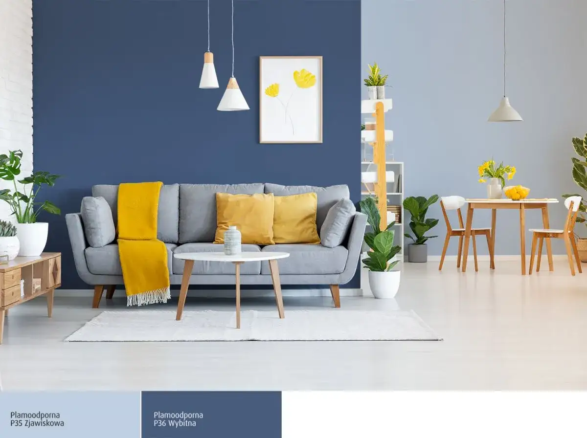 Nowoczesny salon z szarą sofą, żółtymi poduszkami i kocem, ozdobiony roślinami. Ściany w różnych odcieniach niebieskiego tworzą przytulną atmosferę.