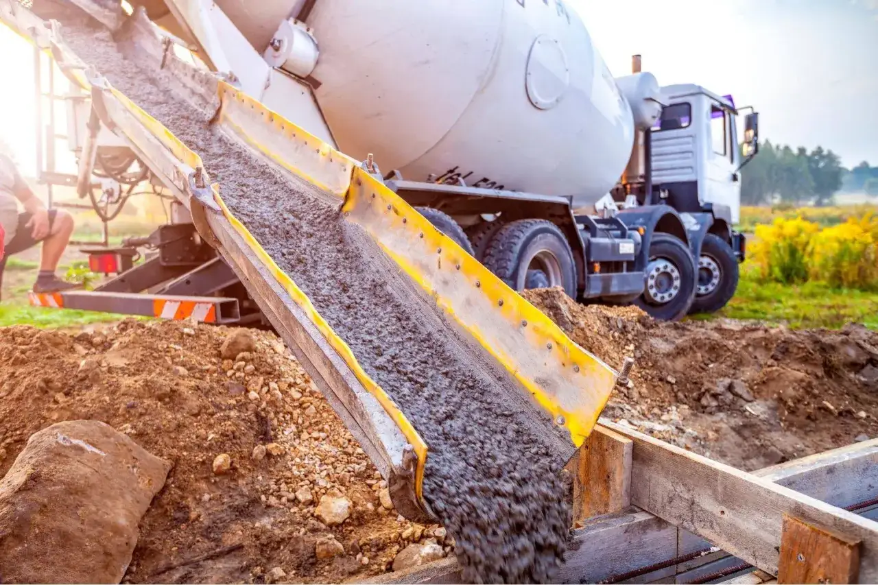 Betoniarka zrzuca beton do szalunku. Prace budowlane trwają, a b30 jest kluczowym elementem fundamentów.