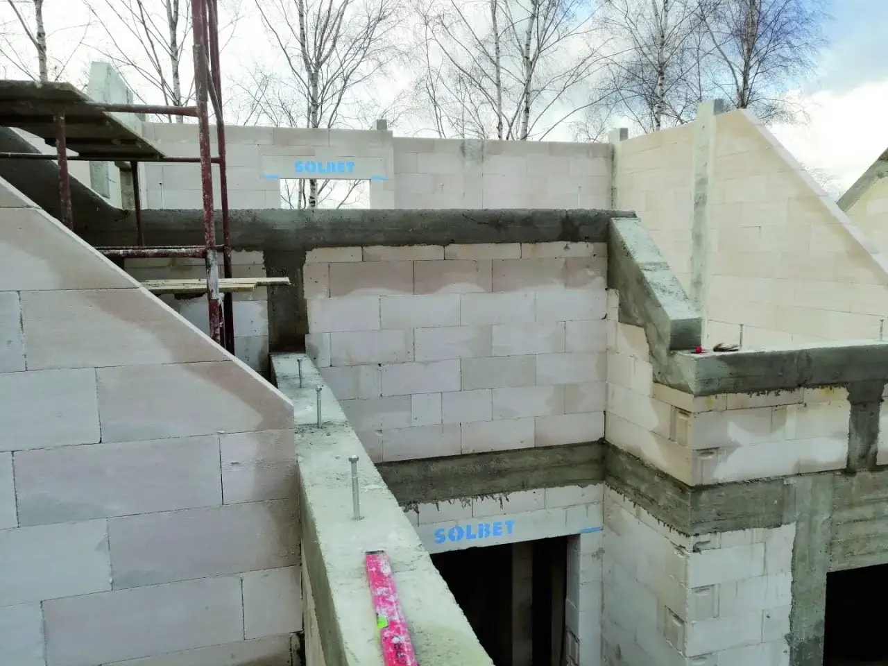 Budowa domu z bloczków betonowych. Widać elementy konstrukcyjne i otwory, które można wypełnić, gdy pojawią się duże ubytki w ścianie wewnętrznej.