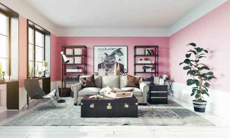 Salon z róż indyjski na ścianach. Wygodna sofa, stylowa skrzynia i regały pełne książek tworzą przytulną atmosferę.