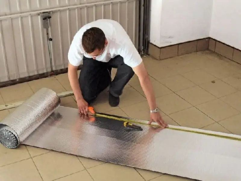 Mężczyzna mierzy materiał do ocieplenia bramy garażowej.